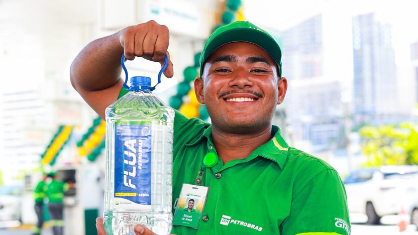 Frentista sorrindo com uma embalagem de FLUA, na campanha da Petrobras