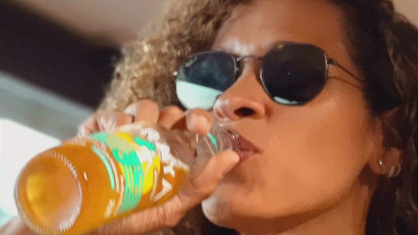 Mulher de óculos escuros bebendo uma cerveja Praya, no vídeo de Heineken e Redemix