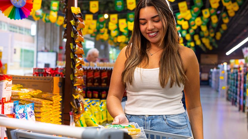 Cliente com o carrinho de compras sob as bandeirinhas de São João, no supermercado da Redemix
