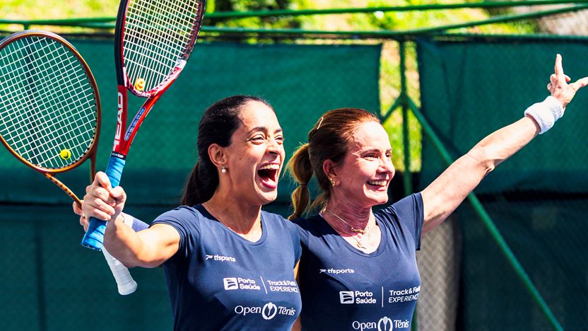 Duas tenistas comemorando na quadra, com as raquetes para o alto, no Open Tênis da Track&Field
